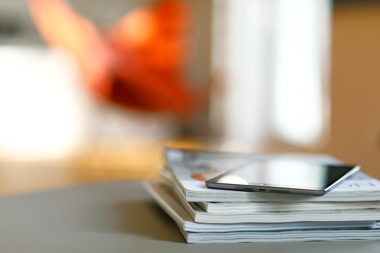 Gray digital tablet on a coffee table, armchair in the background